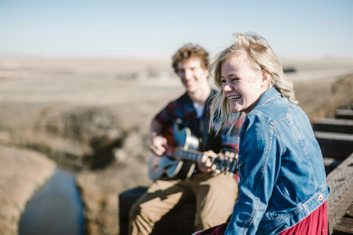 Young musicians playing acoustic guitar outdoors at sunset